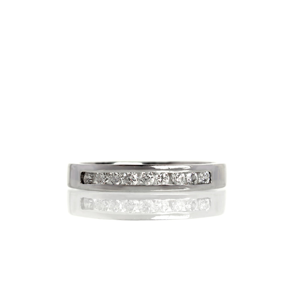 A product photo of a bold, minimalistic half-eternity diamond ring made of solid 9ct white gold. 9 bright white diamonds are embedded along the centre of the band, framed at the top and bottom by solid, squared golden strips.