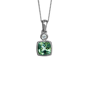 A product photo of a large, 7mm cushion cut mint green tourmaline and diamond pendant suspended by a 9ct white gold chain over a plain white background. The tourmaline stone is a bright, fresh shade of light green, and is set in a thick white golden bezel setting.