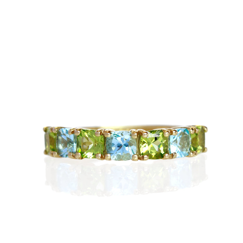 A product photo of a bold, multi-gemstone ring in 9k white gold – made up of 7 blue and green coloured jewels – sitting on a white background.